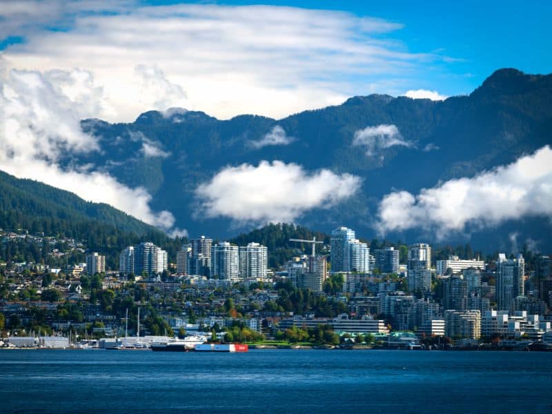 North Vancouver with buildings mixed with water below and the mountains and clouds in the backgroound.
